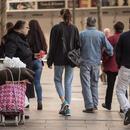 Fotografia persona demanant almoina al carrer, i altres persones caminant